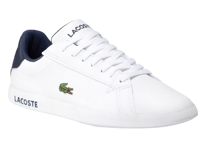 Tenis Lacoste blancos con detalles en azul marino y logotipo de cocodrilo verde en el lateral.