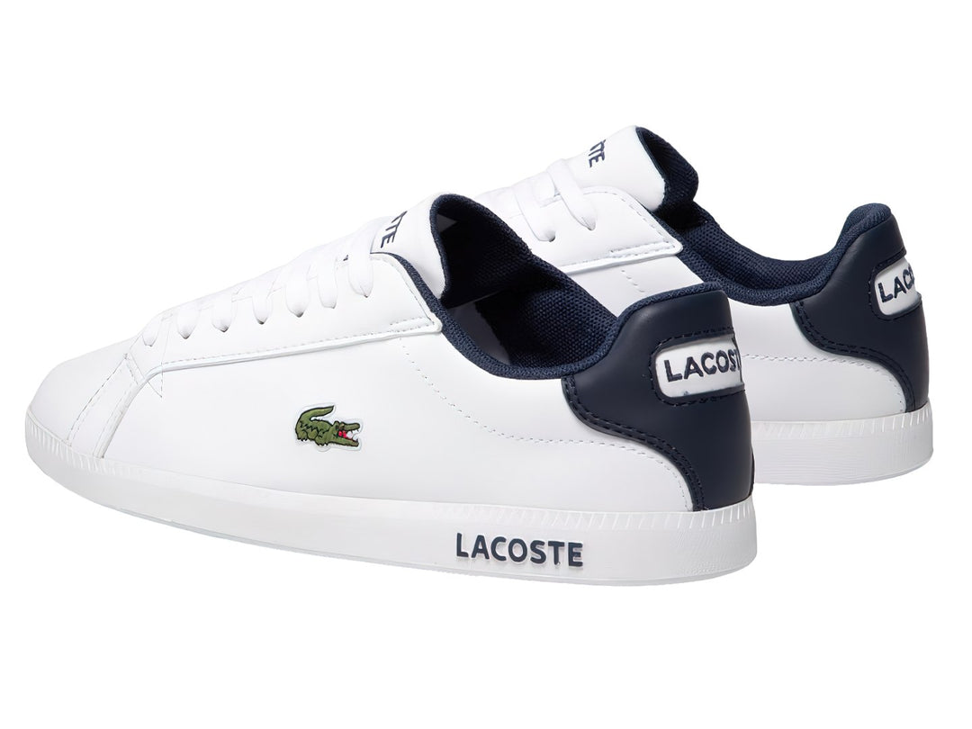 Tenis Lacoste blancos con detalles en azul marino y logotipo de cocodrilo verde en el lateral.