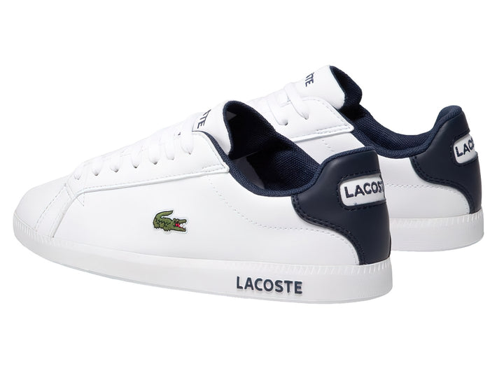 Tenis Lacoste blancos con detalles en azul marino y logotipo de cocodrilo verde en el lateral.