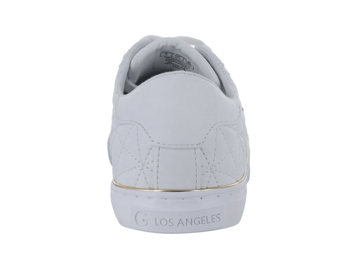 Tenis blancos con detalles dorados y textura acolchada lateral.