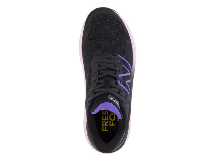 Tenis New Balance color negro con suela gruesa en tono morado claro y detalles en morado.