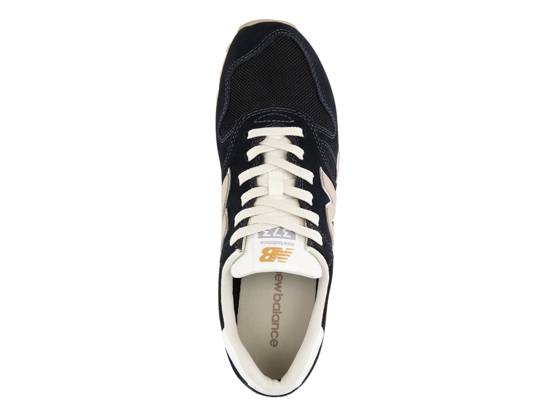 Tenis New Balance modelo 373 en color negro con detalles en blanco y beige, vista lateral.