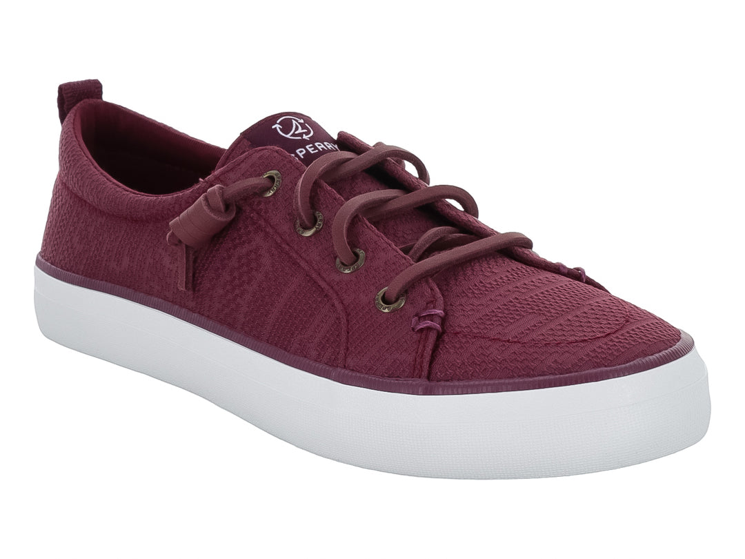 Tenis Sperry color vino con suela blanca y cordones coordinados.