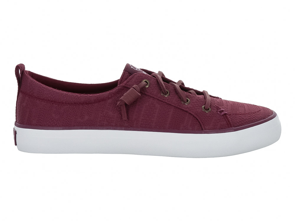 Tenis Sperry color vino con suela blanca y cordones coordinados.