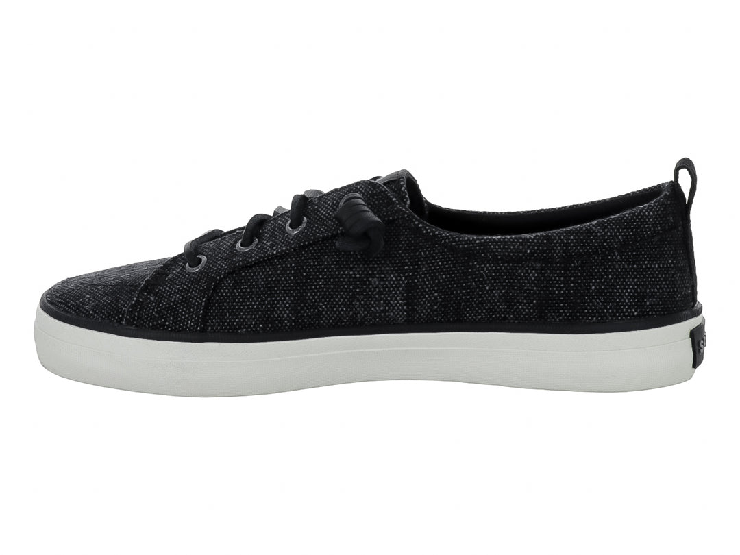 Tenis Sperry color negro de tela con suela blanca y cordones negros.
