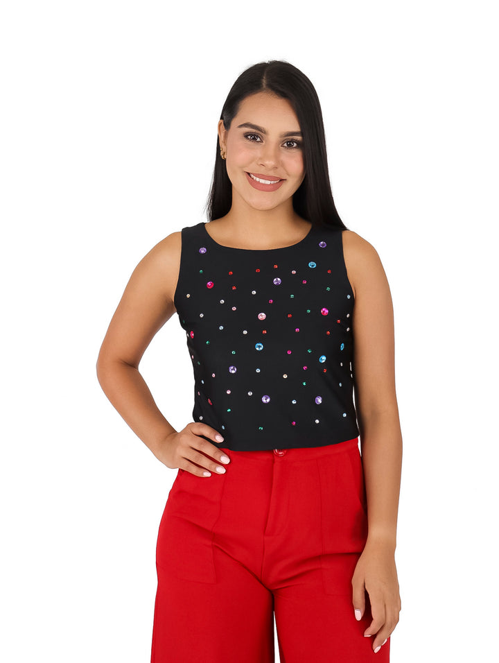 Mujer vistiendo una blusa negra sin mangas adornada con pequeñas piedras multicolores brillantes.