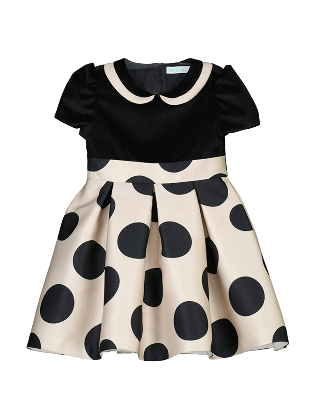 Vestido para niña con top negro y falda beige con lunares negros.