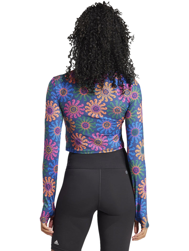 Crop top deportivo de manga larga con estampado floral multicolor sobre fondo azul oscuro.
