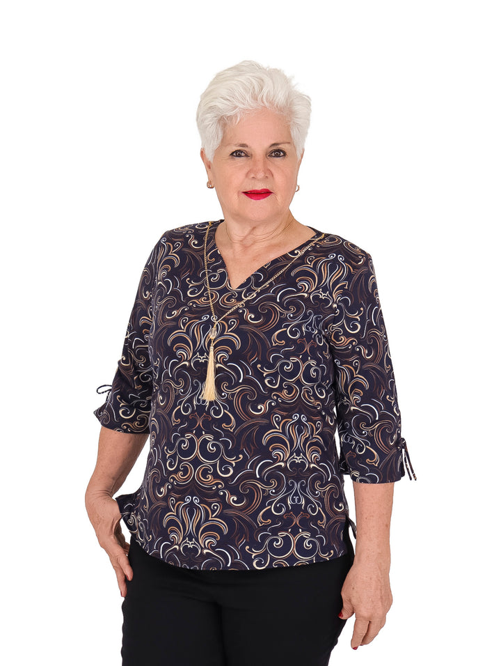 Blusa color marino con estampado en beige y blanco, manga 3/4 y collar decorativo.