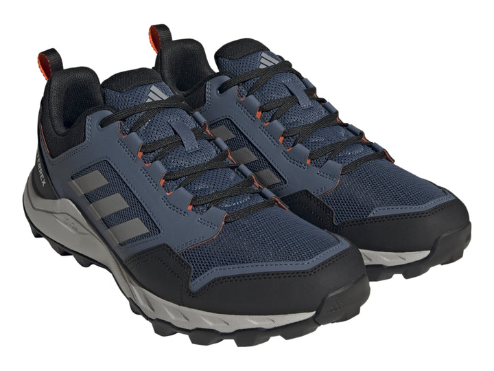 Tenis Adidas Terrex color azul marino y gris con detalles naranja y suela para senderismo.