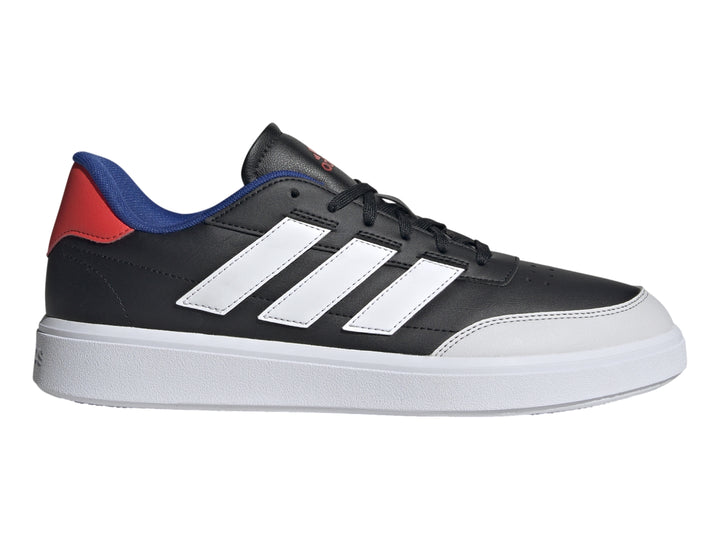 Tenis Adidas Courtblock color negro con tres franjas blancas, suela blanca y detalles en azul y rojo en el talón.