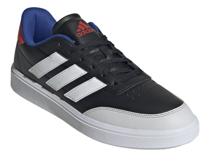 Tenis Adidas Courtblock color negro con tres franjas blancas, suela blanca y detalles en azul y rojo en el talón.