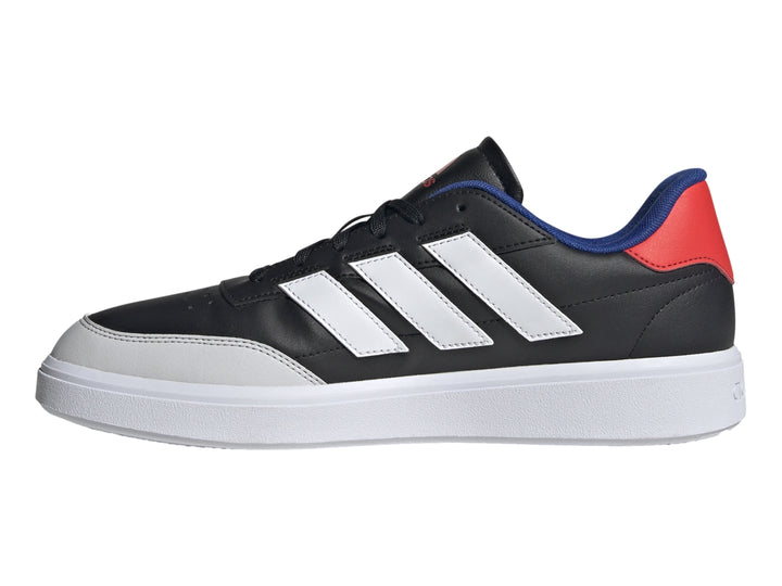 Tenis Adidas Courtblock color negro con tres franjas blancas, suela blanca y detalles en azul y rojo en el talón.