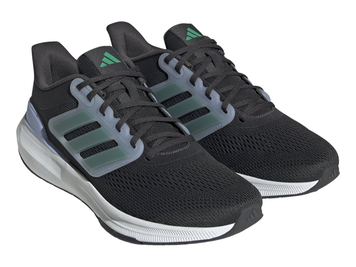 Tenis Adidas Ultrabounce color negro con suela blanca y franjas verdes laterales.