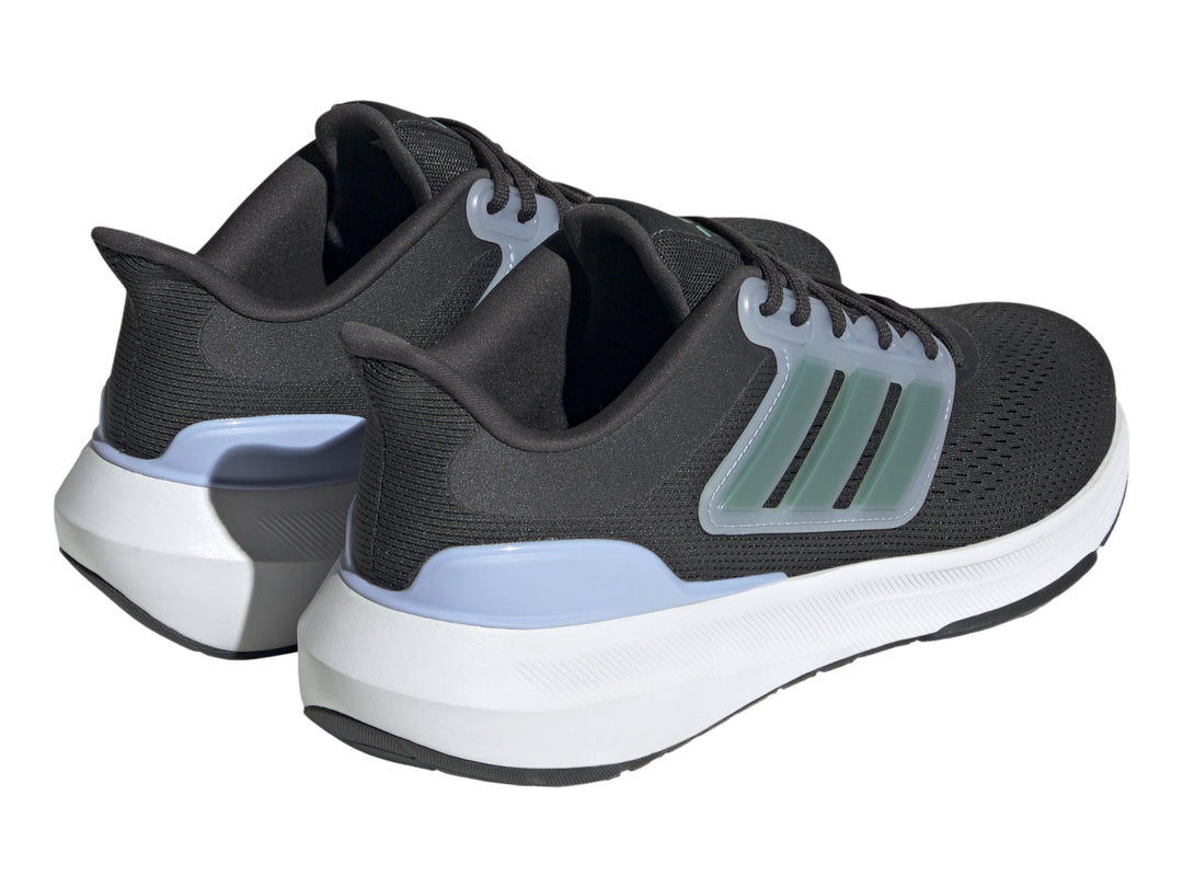 Tenis Adidas Ultrabounce color negro con suela blanca y franjas verdes laterales.