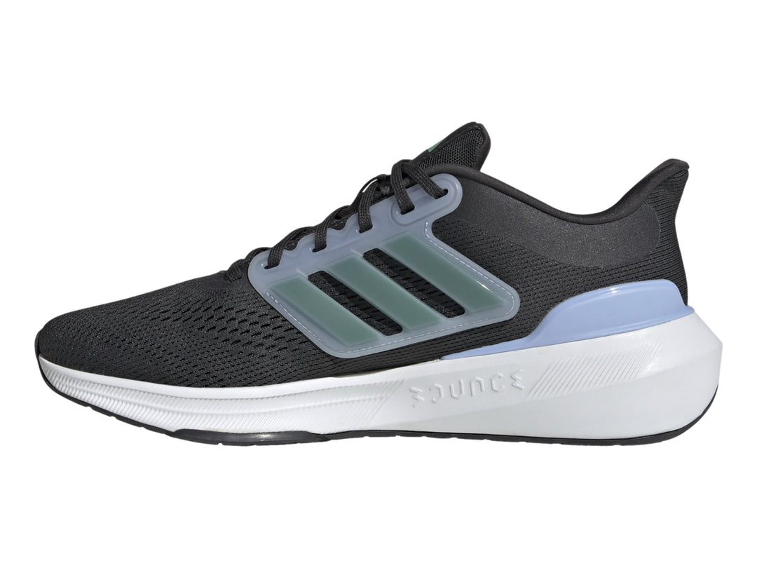 Tenis Adidas Ultrabounce color negro con suela blanca y franjas verdes laterales.