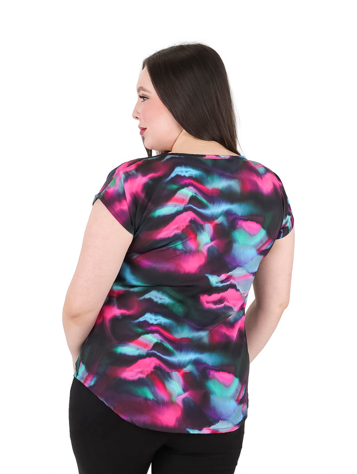 Mujer vistiendo blusa estampada multicolor con cuello en V y manga corta.