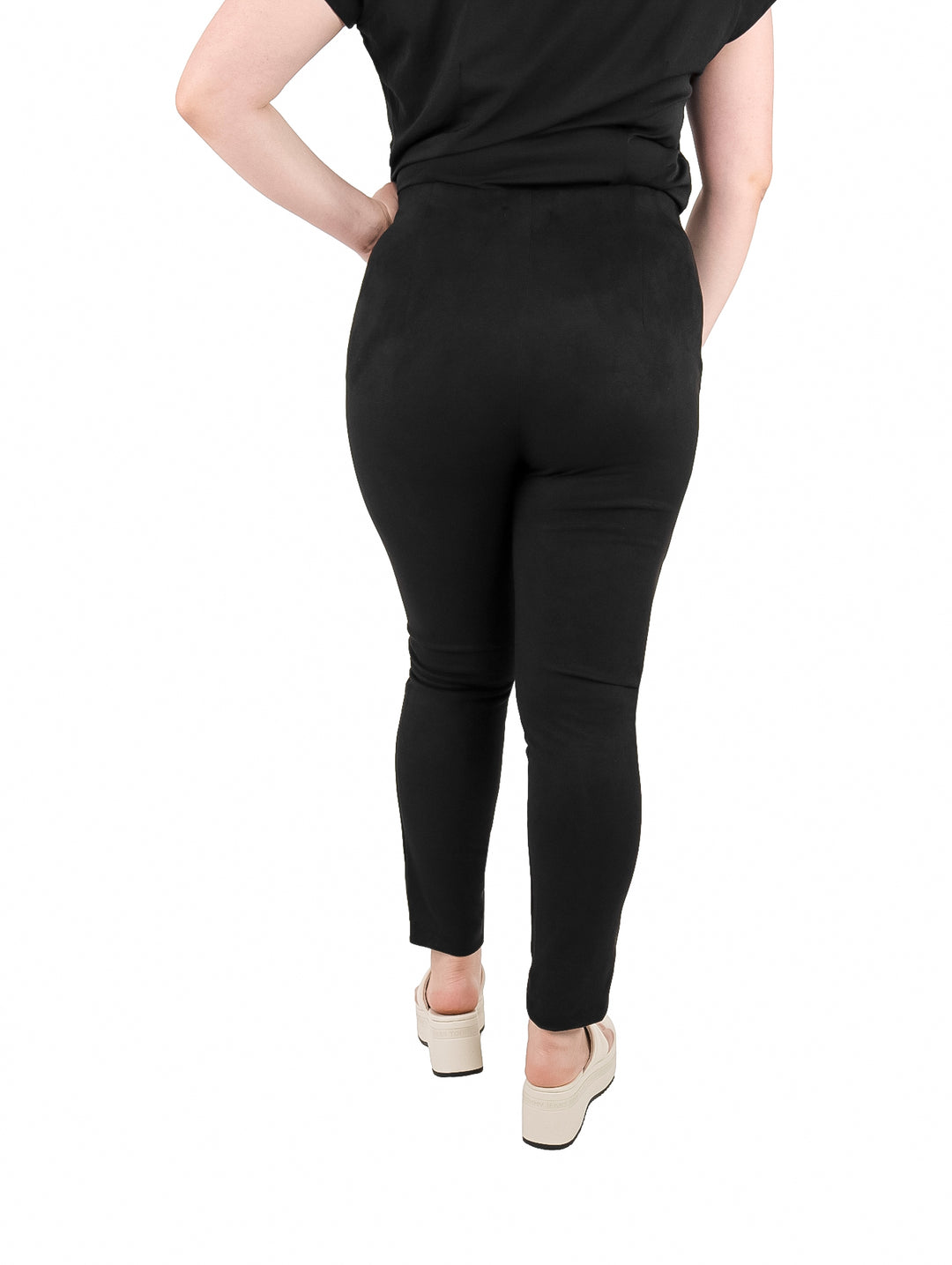 Mujer vistiendo leggings negros de textura mate y sandalias blancas de plataforma.