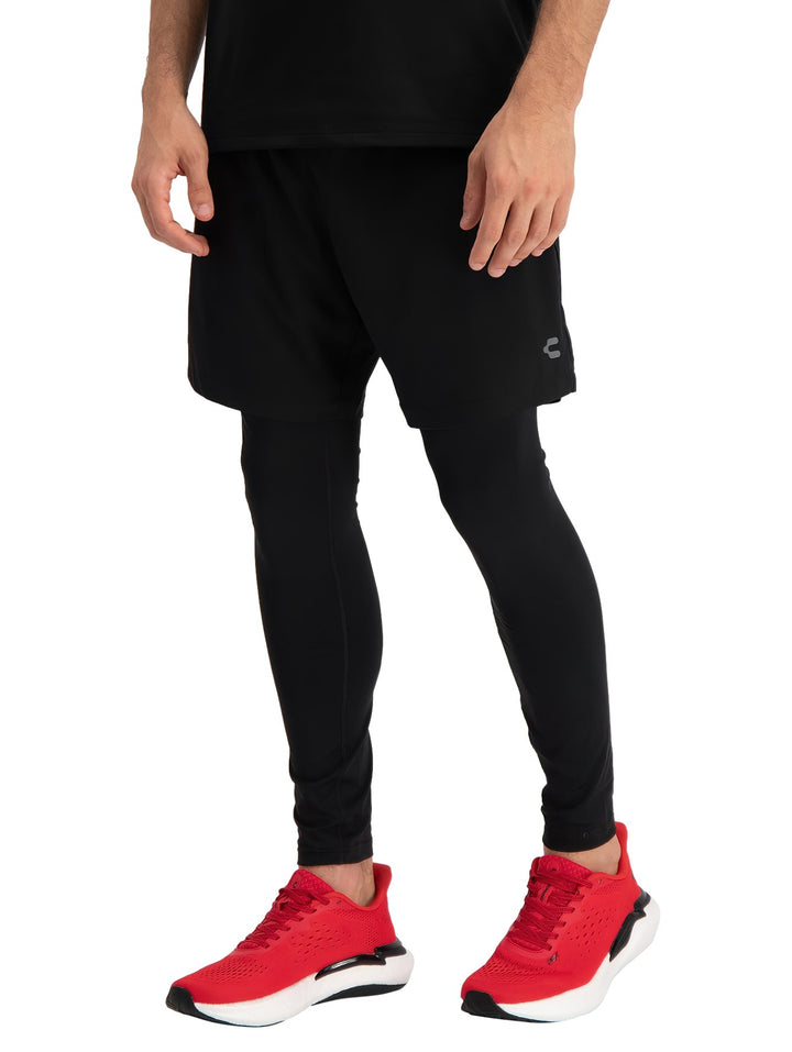 Hombre vistiendo shorts deportivos color negro con leggings y tenis rojos.
