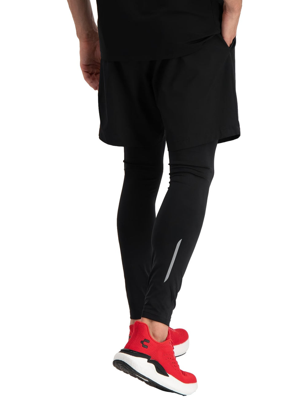 Hombre vistiendo shorts deportivos color negro con leggings y tenis rojos.