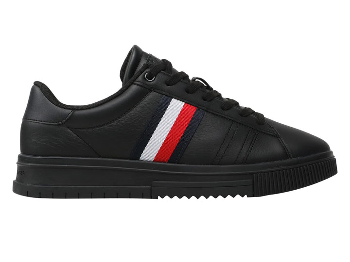 Tenis Tommy Hilfiger de cuero negro con franja tricolor lateral y suela negra.