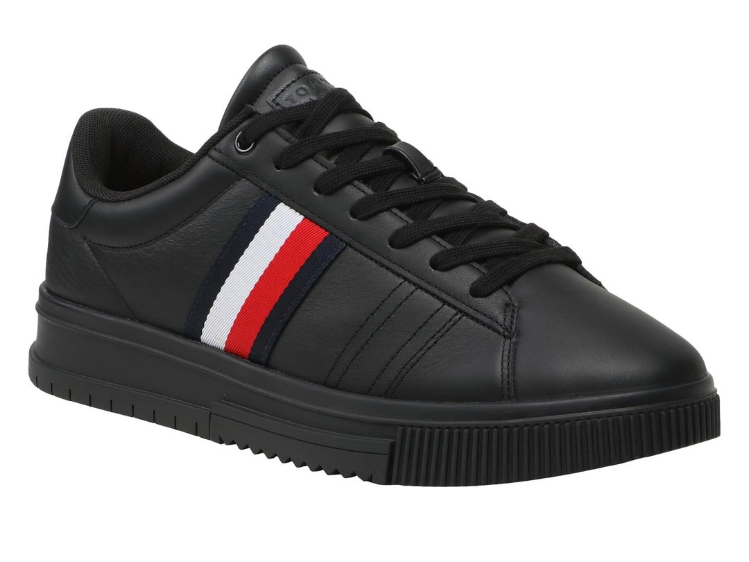Tenis Tommy Hilfiger de cuero negro con franja tricolor lateral y suela negra.