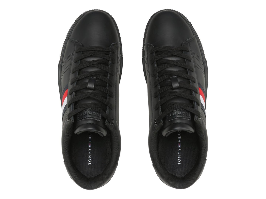 Tenis Tommy Hilfiger de cuero negro con franja tricolor lateral y suela negra.
