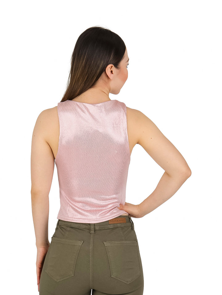 Mujer vistiendo una blusa rosa metálica sin mangas y pantalones cargo color verde oliva.