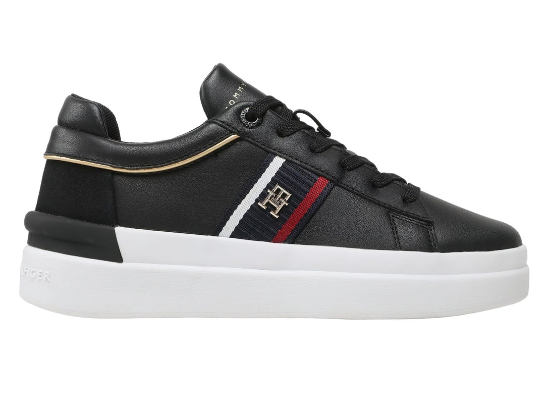 Tenis Tommy Hilfiger negros con suela blanca y detalle de cinta tricolor en el lateral.