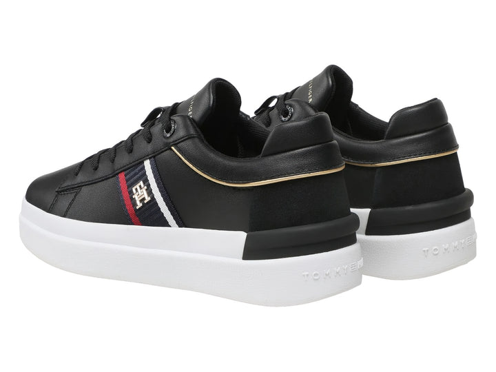 Tenis Tommy Hilfiger negros con suela blanca y detalle de cinta tricolor en el lateral.