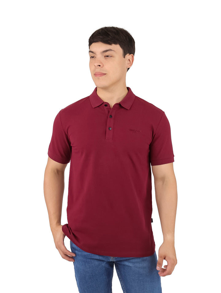 Hombre vistiendo una playera polo de color vino con cuello y manga corta sobre fondo blanco.