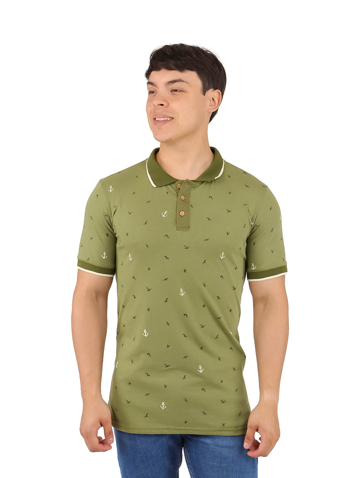 Hombre vistiendo playera polo color verde con estampado de anclas blancas y detalles en el cuello y mangas.