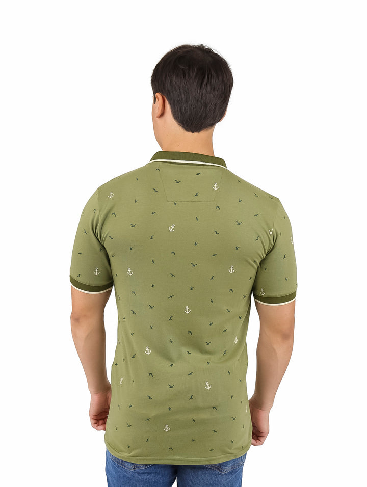 Hombre vistiendo playera polo color verde con estampado de anclas blancas y detalles en el cuello y mangas.