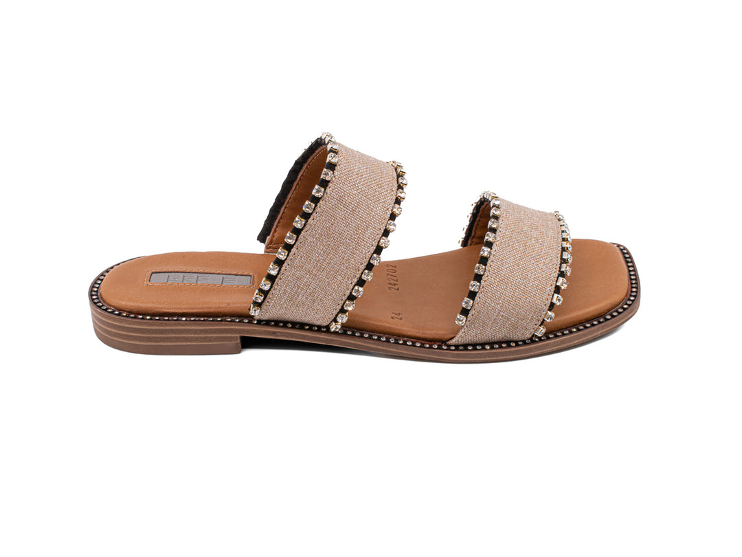 Sandalias slide color crudo con dos bandas decoradas con tachuelas y suela marrón.