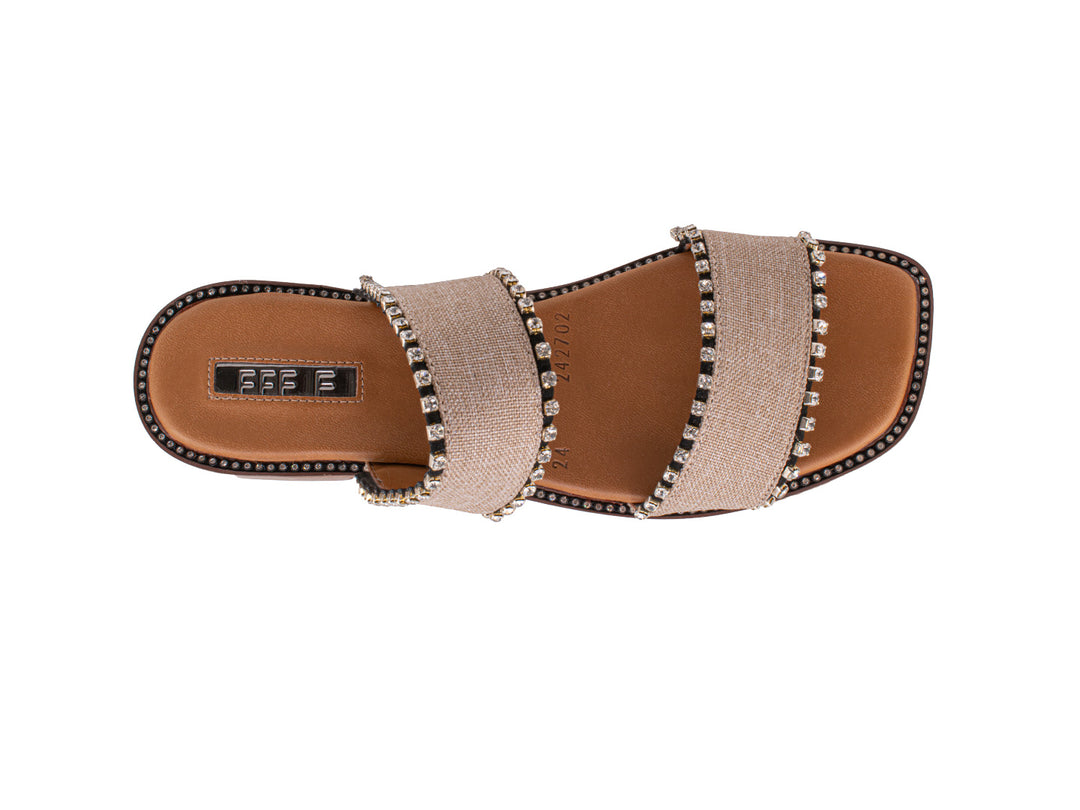 Sandalias slide color crudo con dos bandas decoradas con tachuelas y suela marrón.