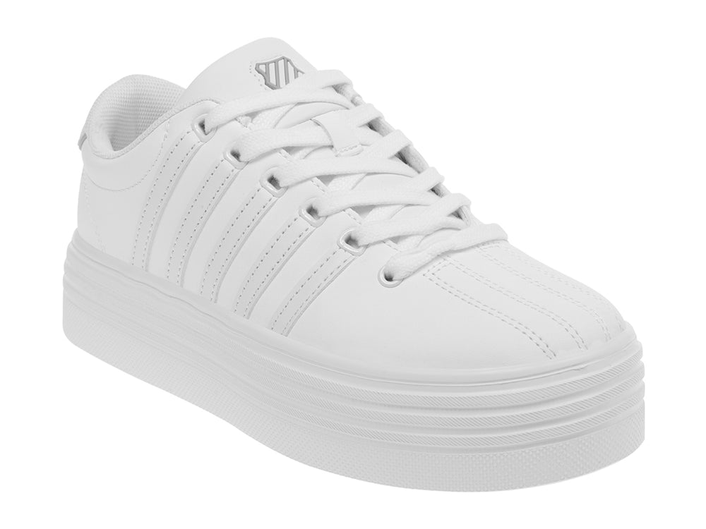 Tenis K-Swiss color blanco con suela de plataforma alta y diseño clásico deportivo.