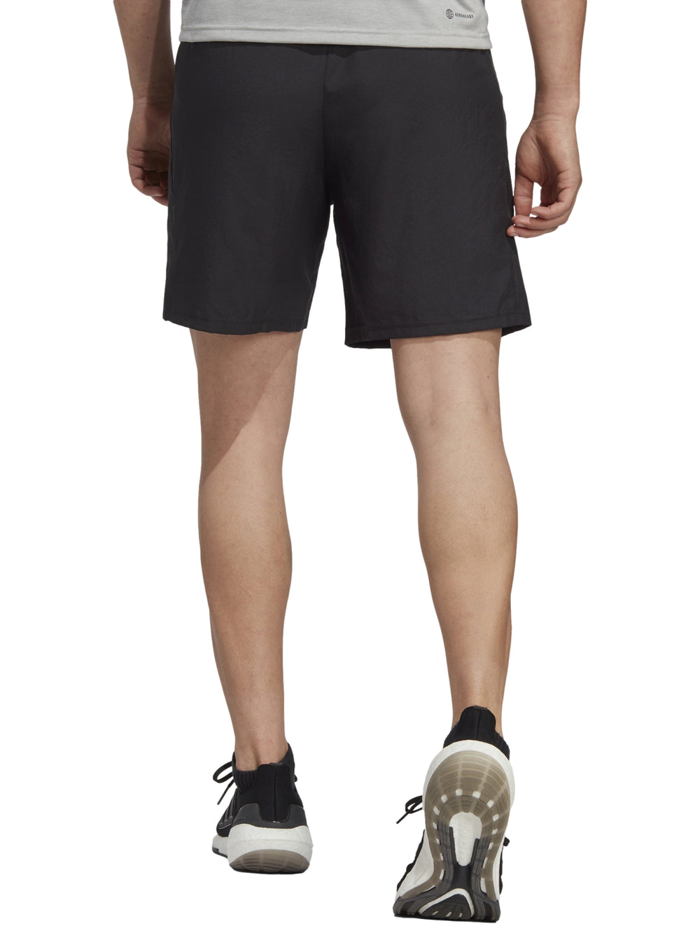 Hombre vistiendo shorts deportivos Adidas de color negro con logo blanco en la pierna izquierda.
