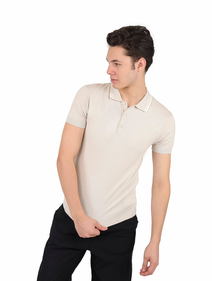 Hombre vistiendo playera polo tejida color arena con pantalones negros.