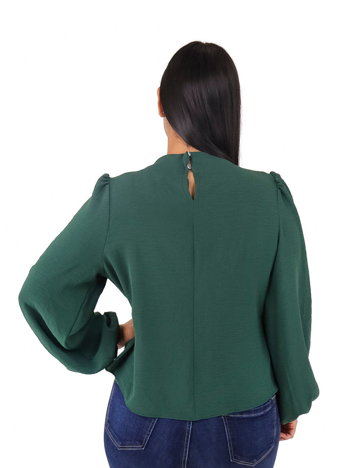 Mujer vistiendo una blusa color verde botella con mangas largas abullonadas y cuello alto.