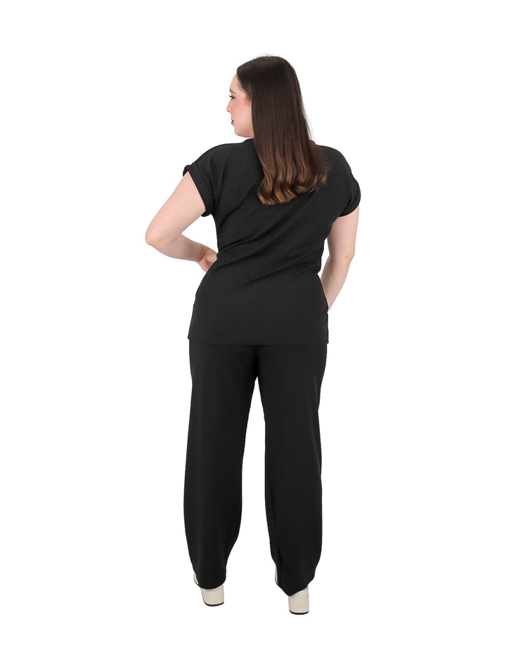Mujer vistiendo un conjunto de dos piezas en color negro compuesto por playera y pantalón.