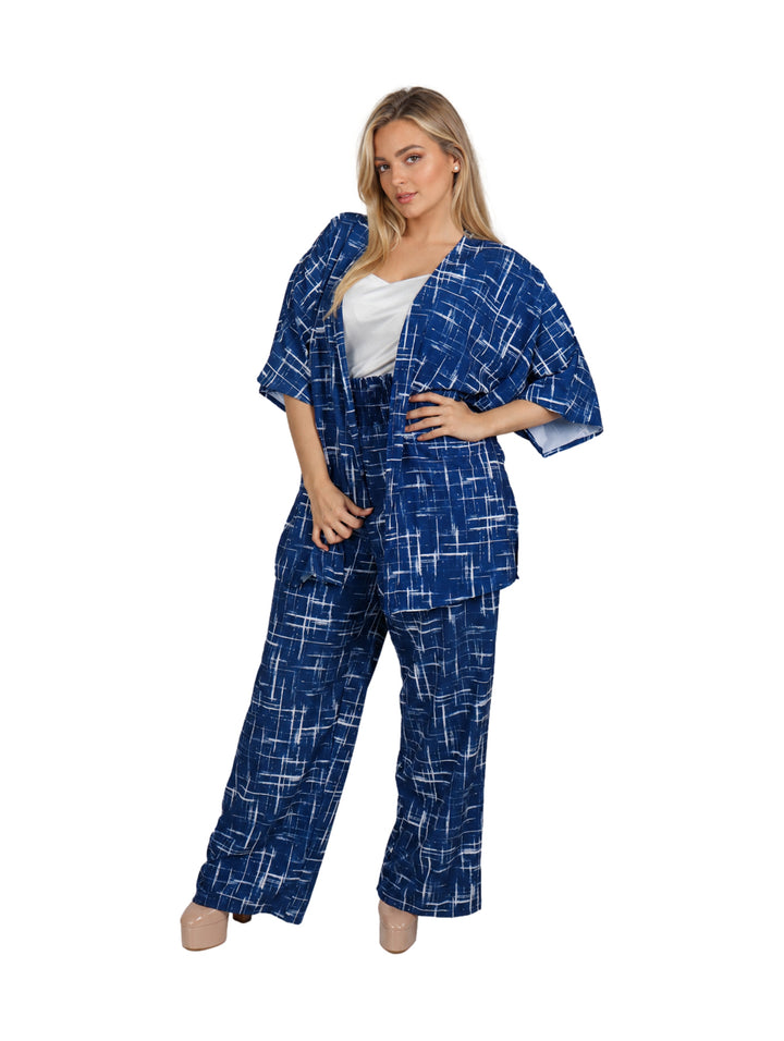 Mujer vistiendo un conjunto de dos piezas azul con estampado geométrico blanco y zapatos beige.