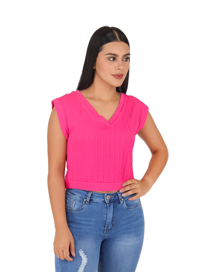 Mujer vistiendo blusa corta color fucsia sin mangas con cuello en V y pantalones vaqueros azules.