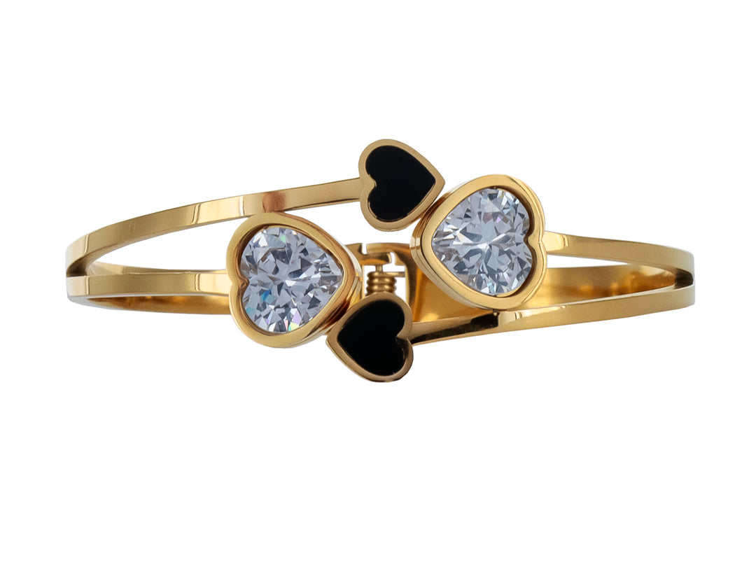 Pulsera rígida color oro con adornos de corazones en color negro y cristal transparente.