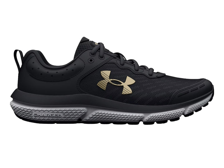 Tenis deportivos Under Armour color negro con suela blanca y logo dorado para niños.