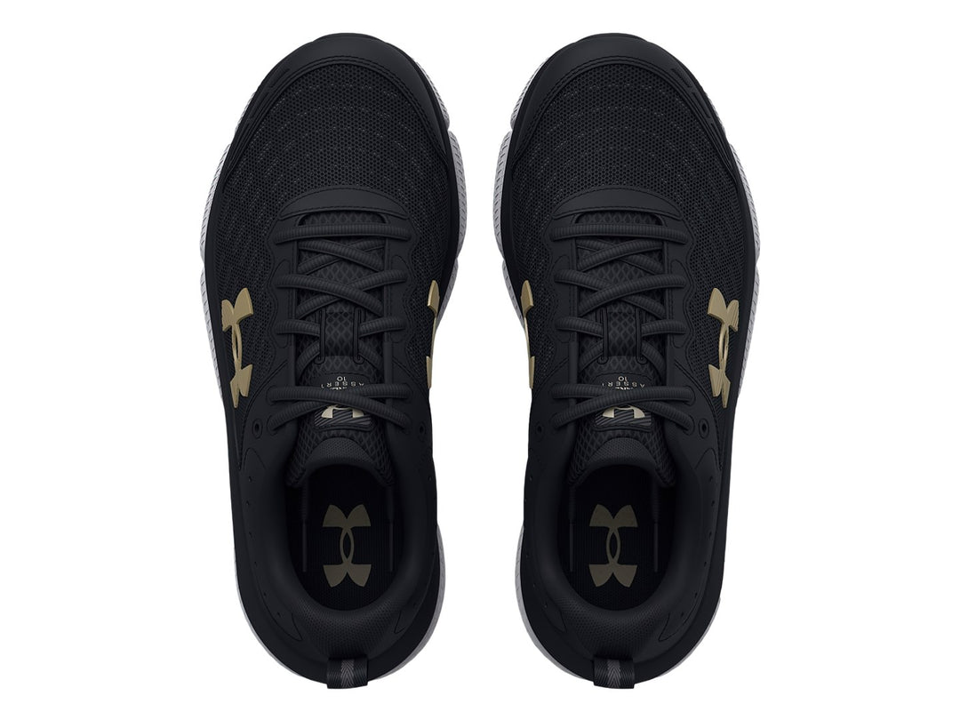 Tenis deportivos Under Armour color negro con suela blanca y logo dorado para niños.