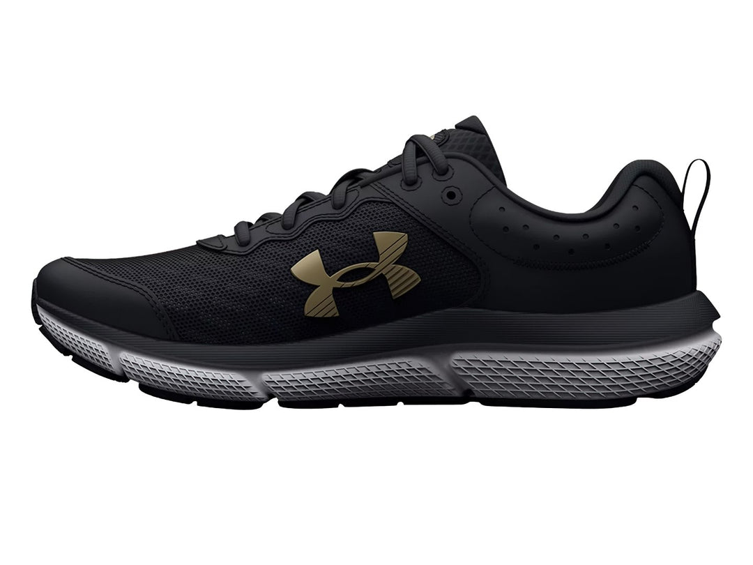 Tenis deportivos Under Armour color negro con suela blanca y logo dorado para niños.