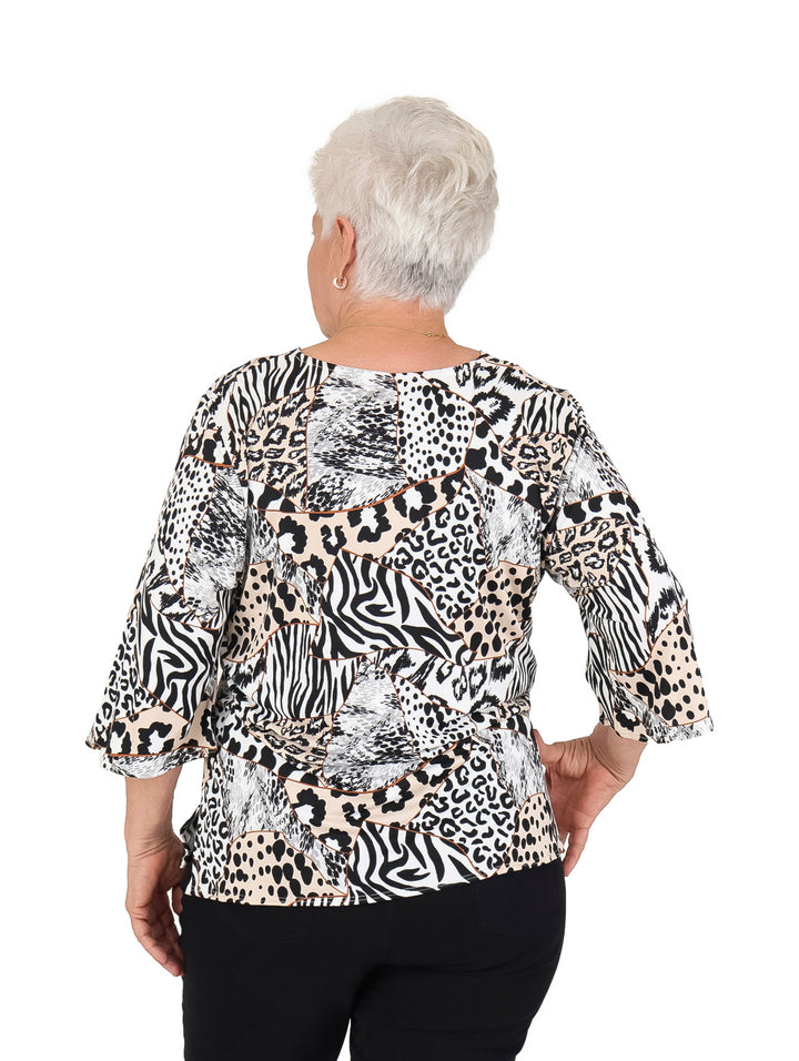 Mujer vistiendo blusa blanca con estampado multicolor de leopardo y cebra, manga 3/4 y cuello en V.