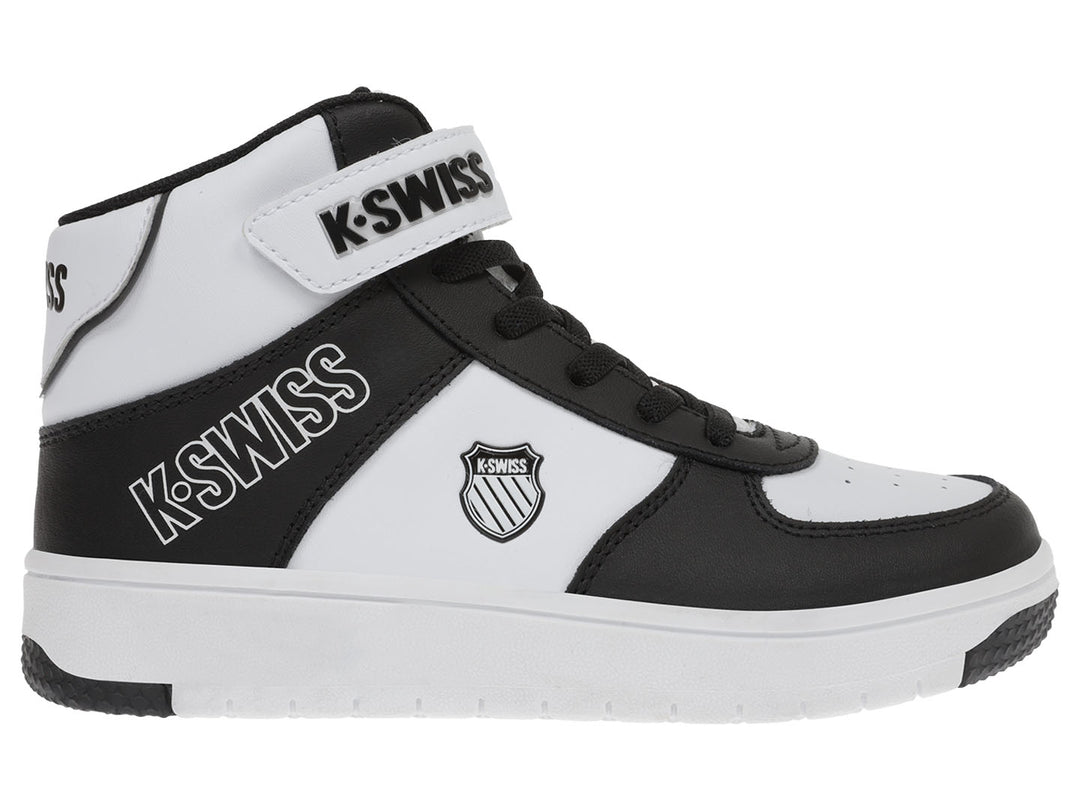 Tenis K-Swiss infantiles en colores blanco y negro, diseño mid-top con correa de velcro y agujetas.