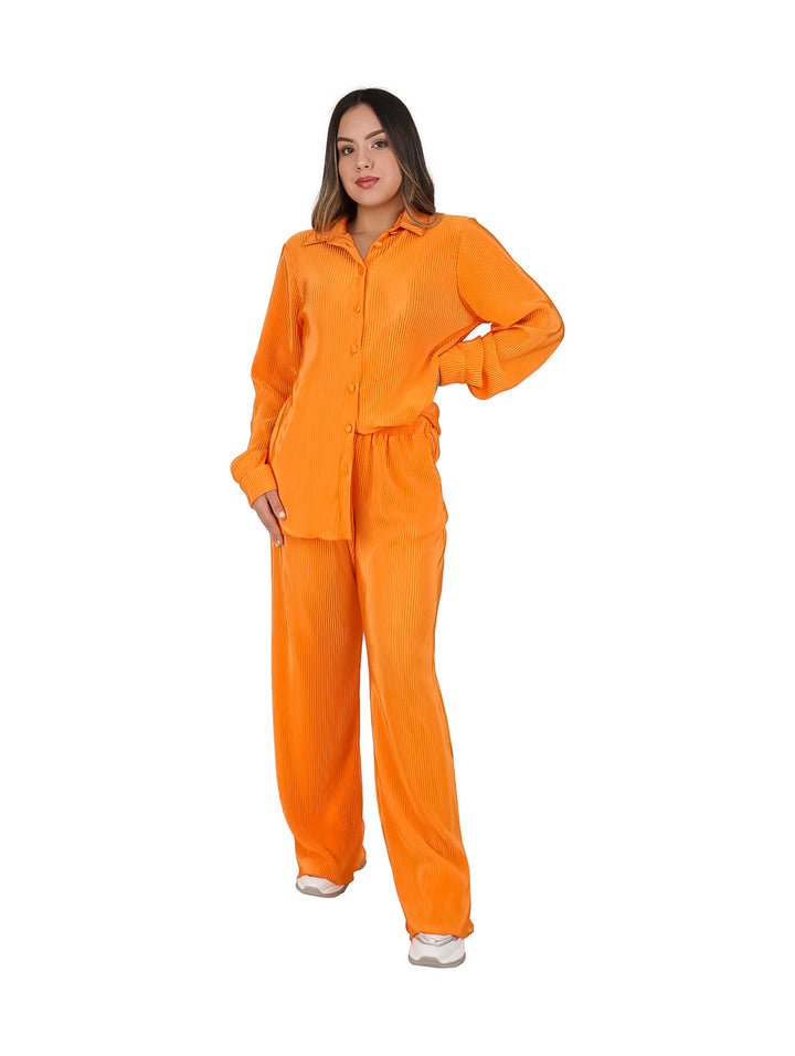 Mujer vistiendo un conjunto de dos piezas color naranja compuesto por blusa camisera y pantalón plisado.