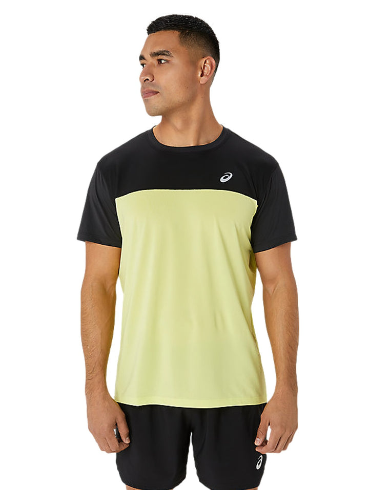 Hombre vistiendo camiseta deportiva ASICS en colores negro y amarillo brillante con shorts negros.